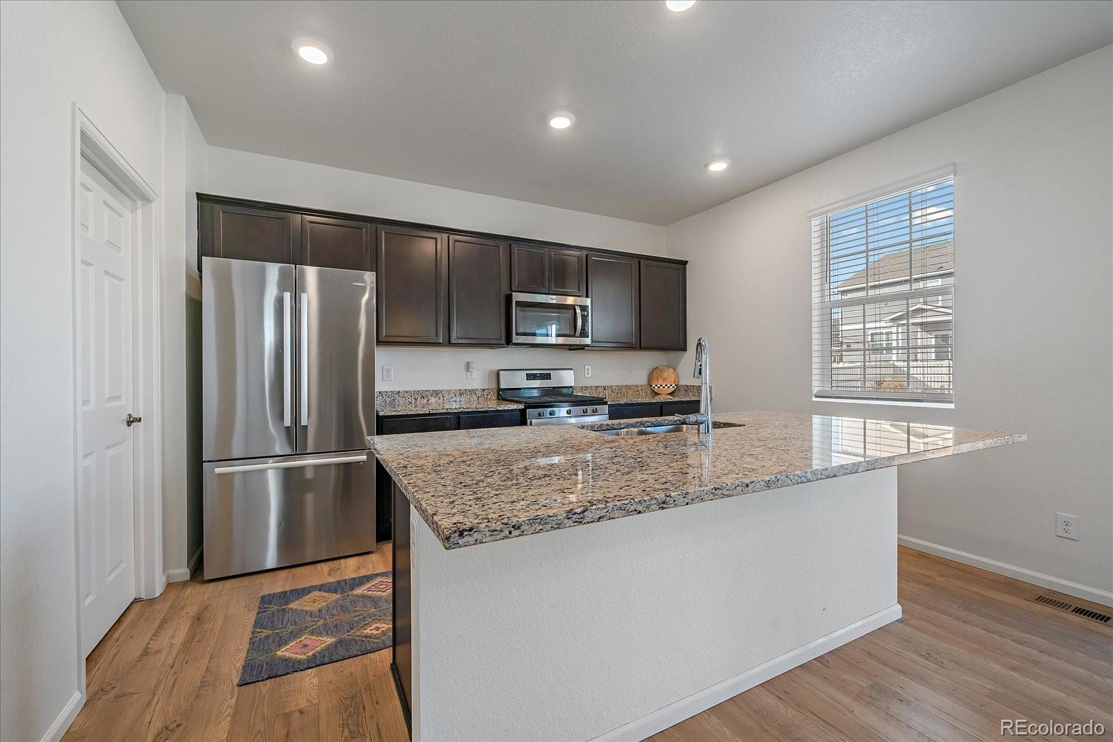 10097 Cedar Street Firestone, CO 80504 - Photo 9 of 37 a kitchen with stainless steel appliances granite countertop a refrigerator a stove a sink and a microwave