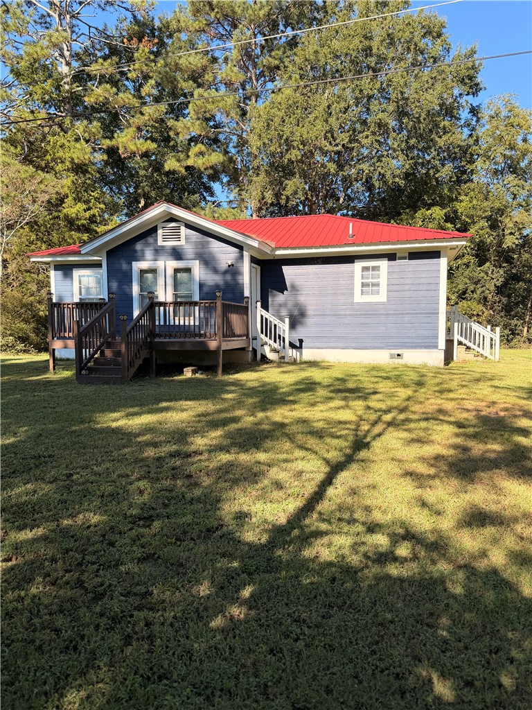 242 Taylor Town Road Abbeville, SC 29620 - Photo 7 of 9 Mature trees frame a charming home featuring a vibrant metal roof and wooden deck.