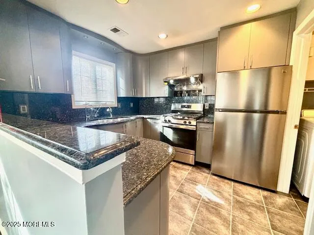 a kitchen with granite countertop a refrigerator a sink dishwasher a stove top oven a refrigerator and cabinets