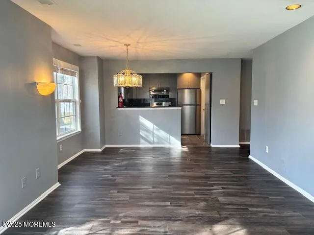 a view of empty room with wooden floor and window