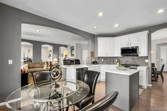 a kitchen with a stove a sink and white cabinets with wooden floor