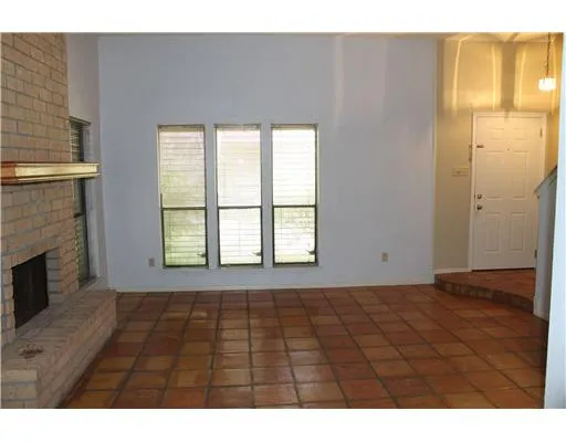 a view of an empty room with wooden floor and a fireplace
