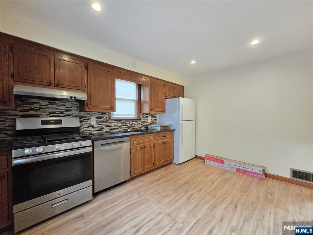701 4th Street Secaucus, NJ 07094 - Photo 5 of 21 a kitchen with granite countertop a stove a sink dishwasher and a refrigerator with wooden floor