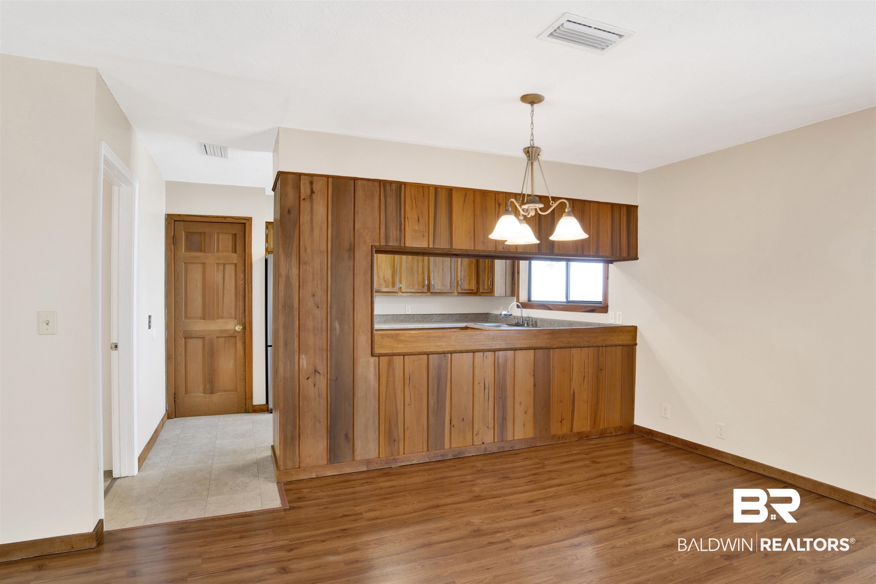 7411 Bay Road Mobile, AL 36605 - Photo 13 of 34 Kitchen with brown cabinetry, decorative light fixtures, a peninsula, light wood-style flooring, and a chandelier