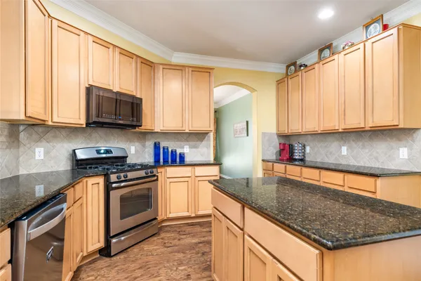 a kitchen with stainless steel appliances granite countertop a stove a sink and a microwave
