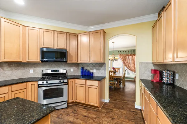 a kitchen with stainless steel appliances granite countertop a stove a sink and a microwave