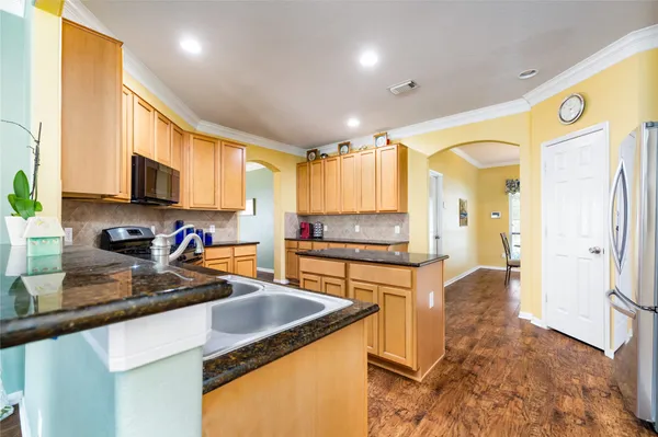 a kitchen with stainless steel appliances granite countertop sink stove refrigerator and cabinets