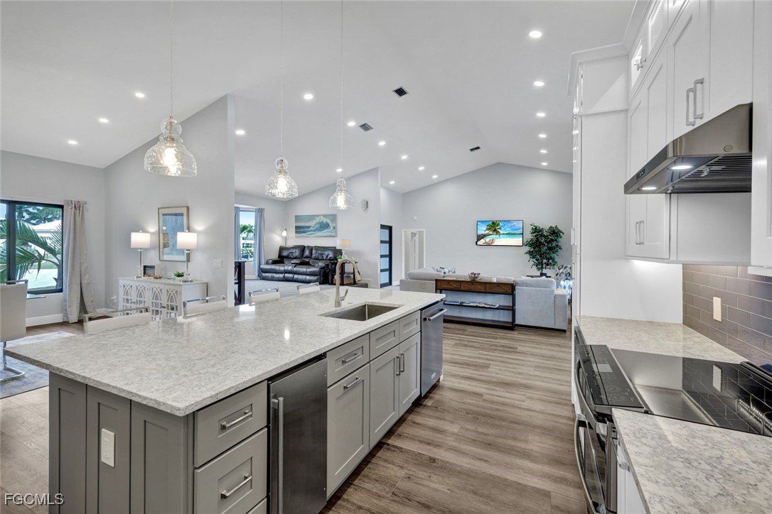5346 Southwest 10th Avenue Cape Coral, FL 33914 - Photo 11 of 50 a large kitchen with kitchen island a large counter top space a sink stainless steel appliances and cabinets