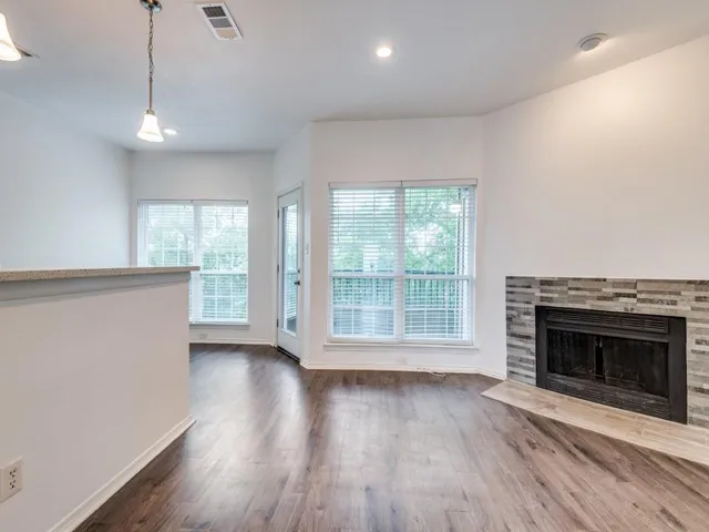 an empty room with wooden floor fireplace and windows