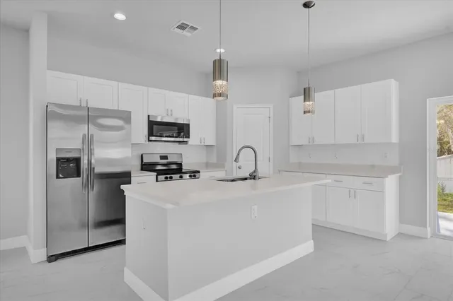 a kitchen with stainless steel appliances granite countertop a refrigerator a stove a sink dishwasher a oven with white cabinets