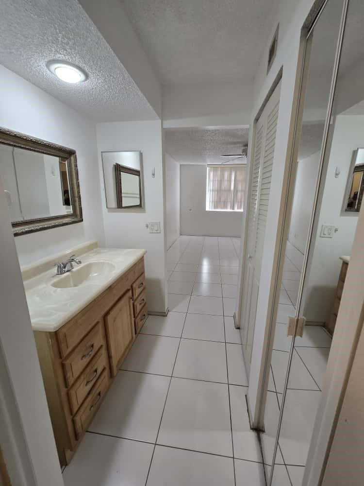 6195 Rock Island Road, Unit 209 Tamarac, FL 33319 - Photo 24 of 40 a bathroom with a sink a toilet and mirror