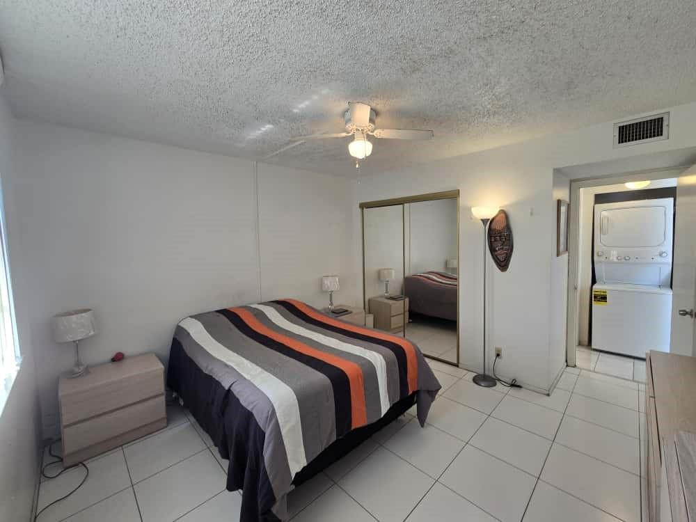 6195 Rock Island Road, Unit 209 Tamarac, FL 33319 - Photo 34 of 40 a bedroom with a bed and a chandelier