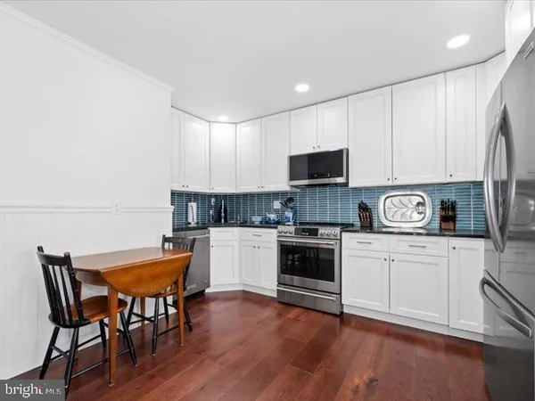 a kitchen with stainless steel appliances granite countertop a white table chairs and a refrigerator