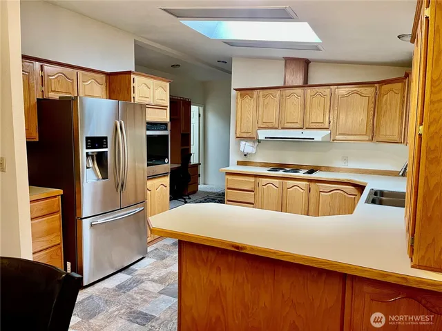 a kitchen with stainless steel appliances granite countertop a refrigerator a sink and a stove