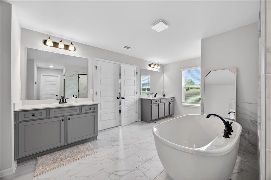 150 Buffalo Trace Stockbridge, GA 30281 - Photo 29 of 35 a spacious bathroom with a double vanity sink a mirror a bathtub and a shower
