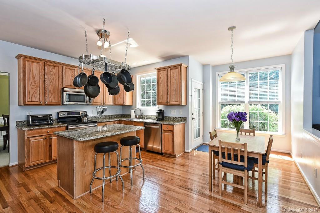 4719 Lapis Court Fort Mill, SC 29708 - Photo 8 of 24 a kitchen with stainless steel appliances granite countertop a stove top oven a refrigerator a dining table and chairs with wooden floor