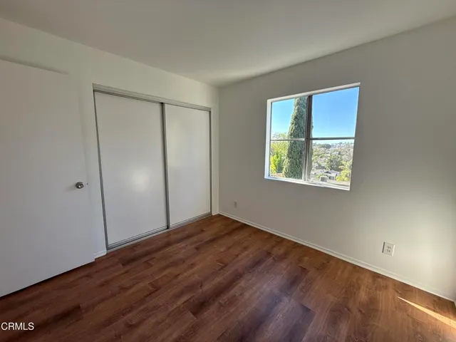 an empty room with wooden floor closet and windows