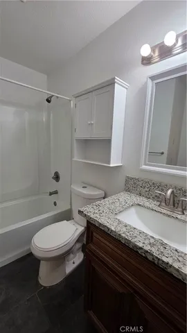 a bathroom with a granite countertop toilet sink and mirror