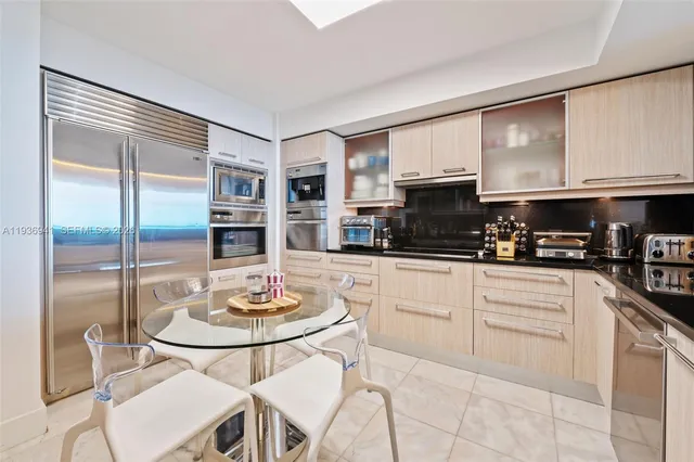 a kitchen with stainless steel appliances granite countertop a stove a refrigerator a dining table and chairs with wooden floor