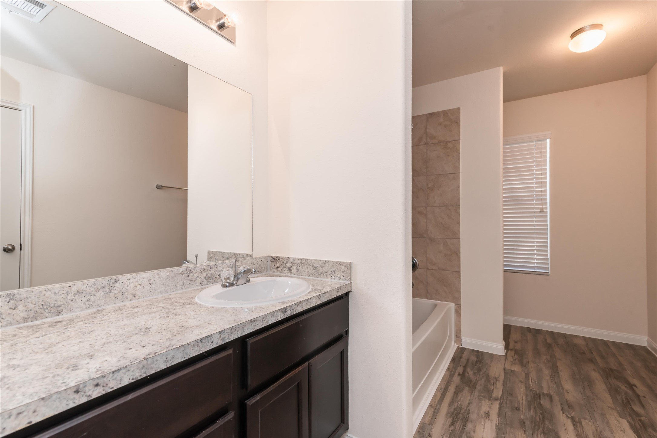 24322 Amaldi Court Katy, TX 77493 - Photo 6 of 8 a bathroom with a granite countertop sink a mirror and wooden floor