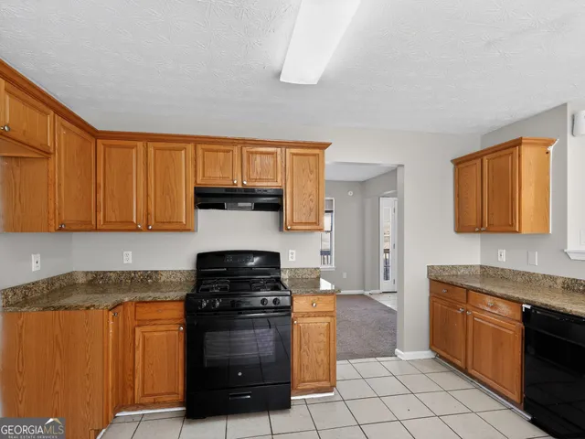 a kitchen with granite countertop a refrigerator stove top oven and sink