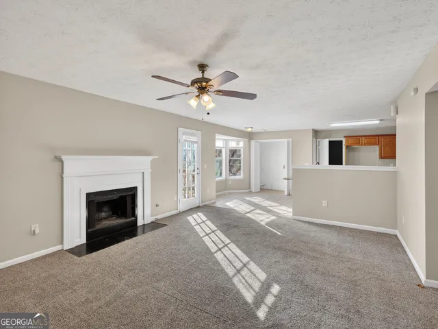 a view of a livingroom with a fireplace a ceiling fan and windows