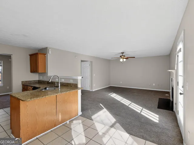 a kitchen with granite countertop a sink a stove top oven and cabinetry
