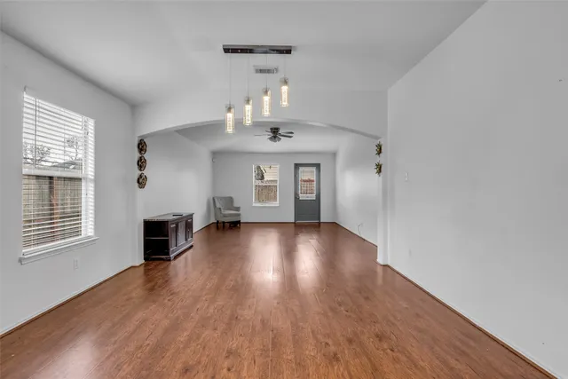 a view of an empty room with wooden floor fireplace and a window
