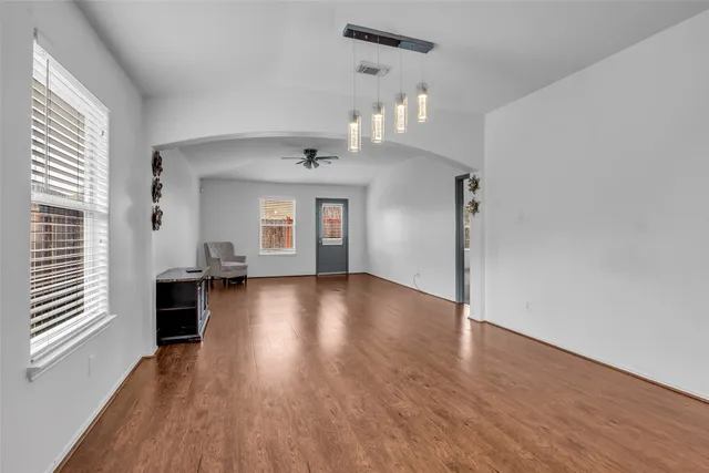 an empty room with wooden floor and windows