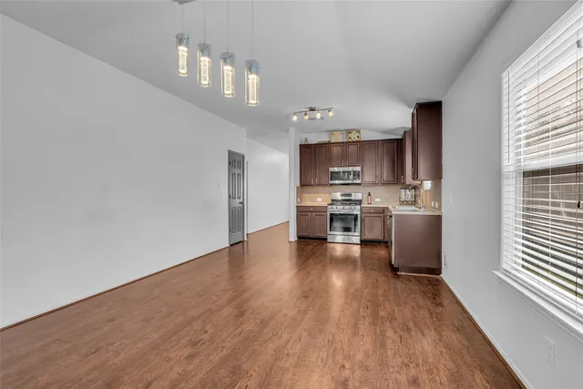 a kitchen with stainless steel appliances a lot of cabinets and wooden floor