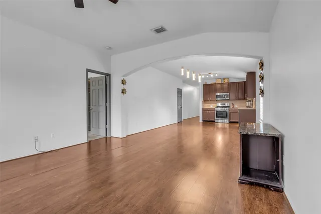 a view of a room with wooden floor kitchen view and a window