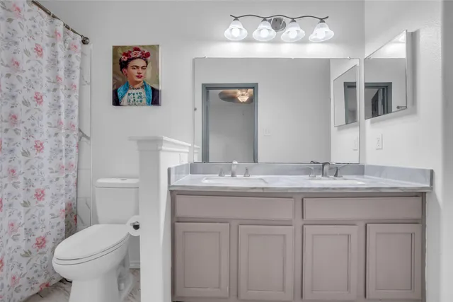 a bathroom with a granite countertop toilet sink and mirror