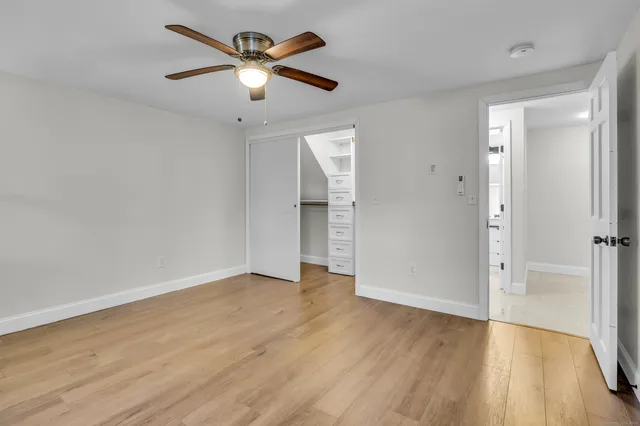 an empty room with wooden floor and a ceiling fan