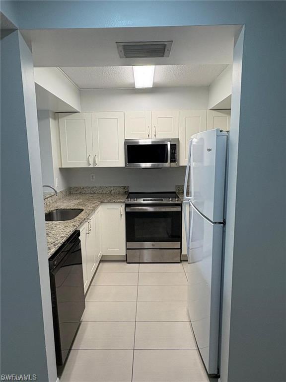 109 Wading Bird Circle, Unit V102 Naples, FL 34110 - Photo 8 of 15 a kitchen with granite countertop a refrigerator and a stove top oven