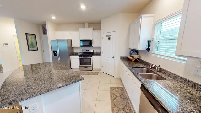 a kitchen with granite countertop a sink a counter top space appliances and cabinets