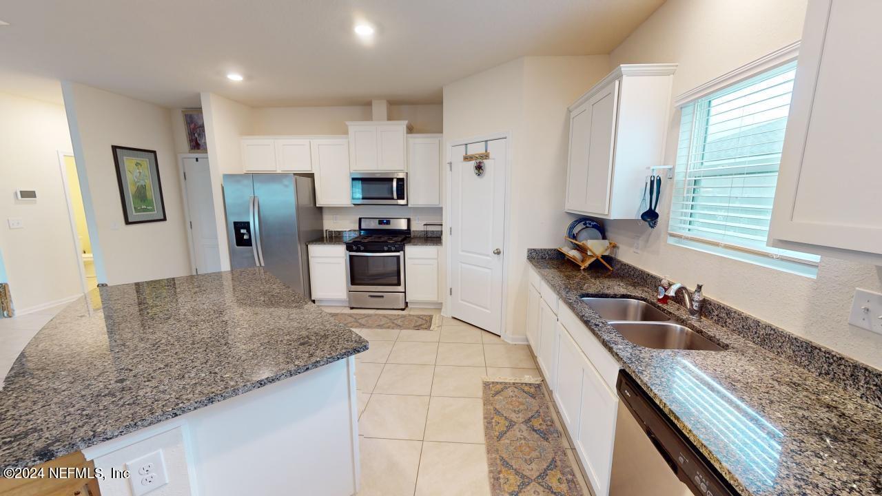 86013 Club Car Place Yulee, FL 32097 - Photo 12 of 28 a kitchen with granite countertop a sink a counter top space appliances and cabinets