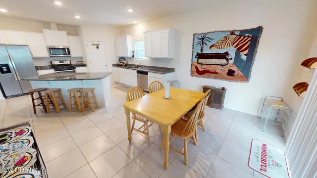 a kitchen with stainless steel appliances granite countertop a sink a stove a refrigerator white cabinets and wooden floor