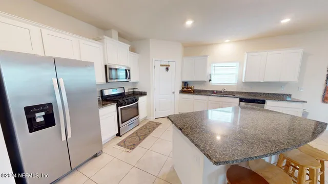 a kitchen with stainless steel appliances granite countertop a refrigerator a stove and a sink