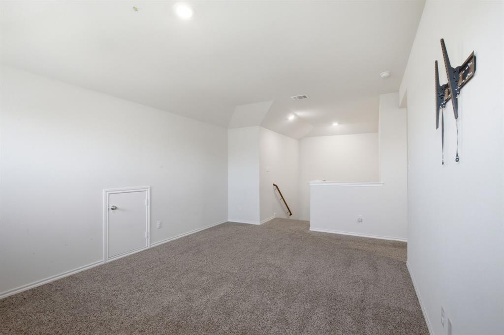 1328 Broaddus Road Forney, TX 75126 - Photo 6 of 31 Carpeted room with a staircase featuring a white half-wall and a dark wood handrail
