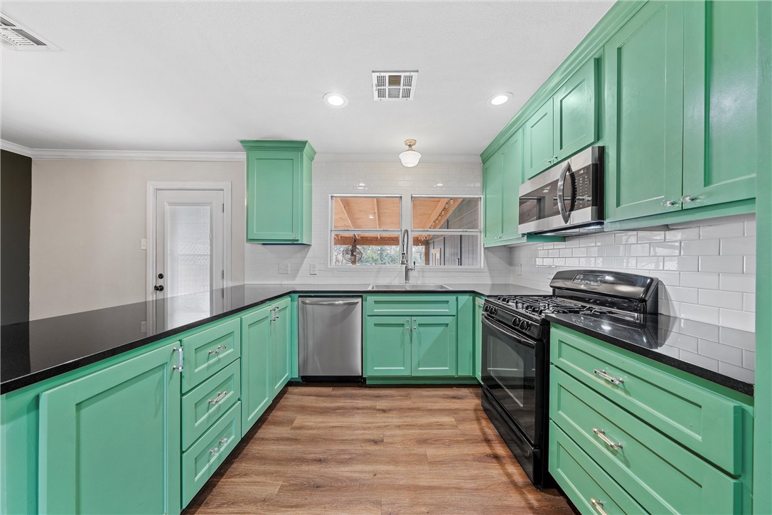 3100 Colonial Avenue Waco, TX 76707 - Photo 4 of 15 a kitchen with kitchen island wooden cabinets stainless steel appliances and a sink