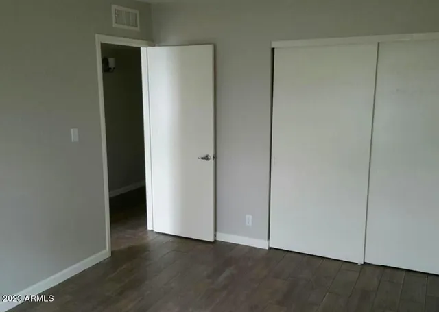 an empty room with wooden floor and closet