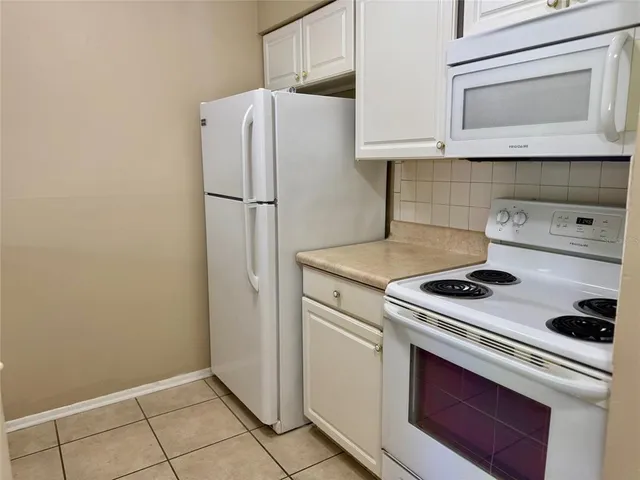 a white refrigerator freezer and a stove sitting inside of a kitchen