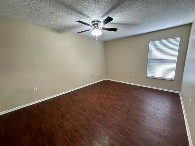 an empty room with wooden floor fan and windows
