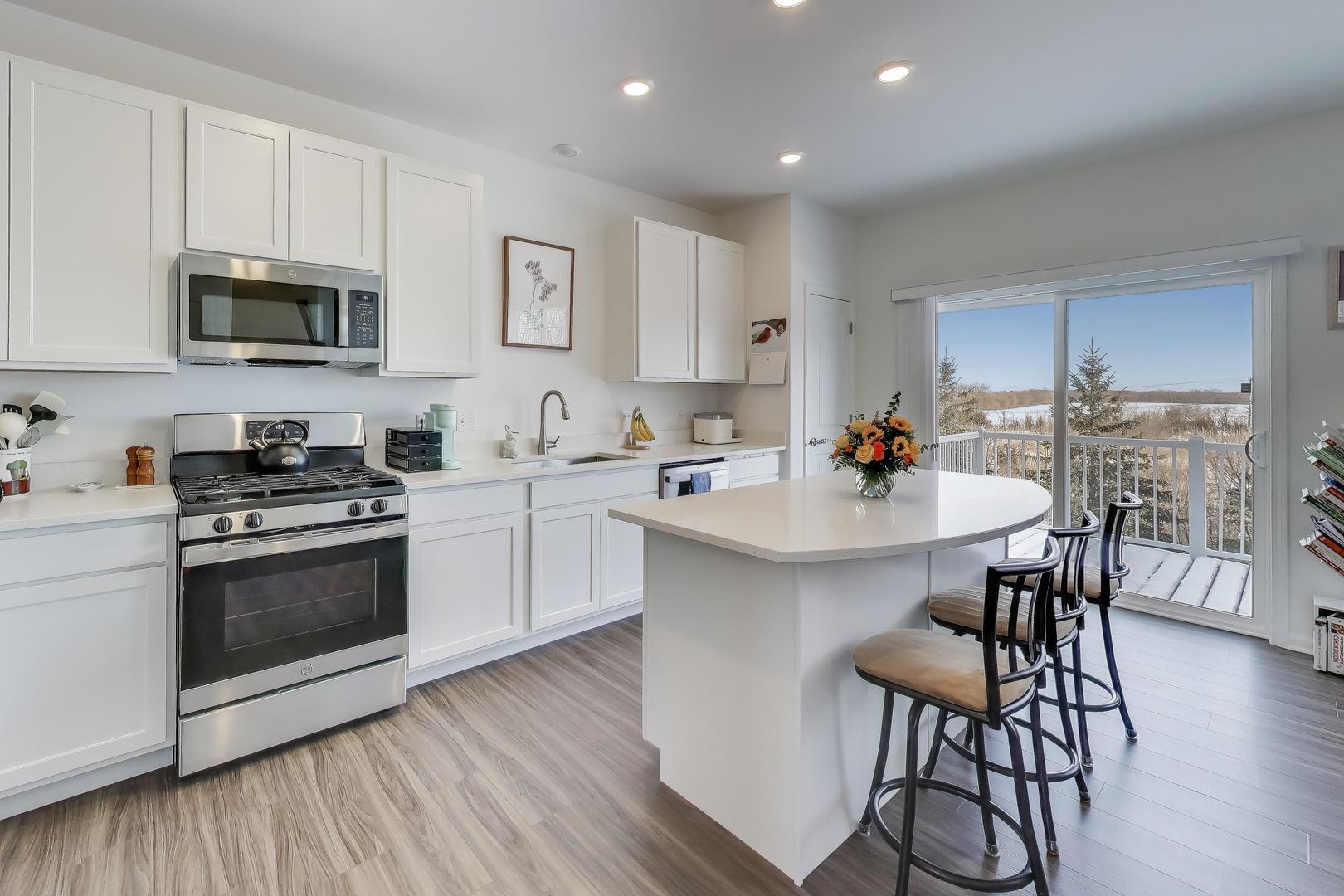 709 Neubauer Circle Lindenhurst, IL 60046 - Photo 8 of 25 a kitchen with stainless steel appliances a white table chairs and a wooden floor