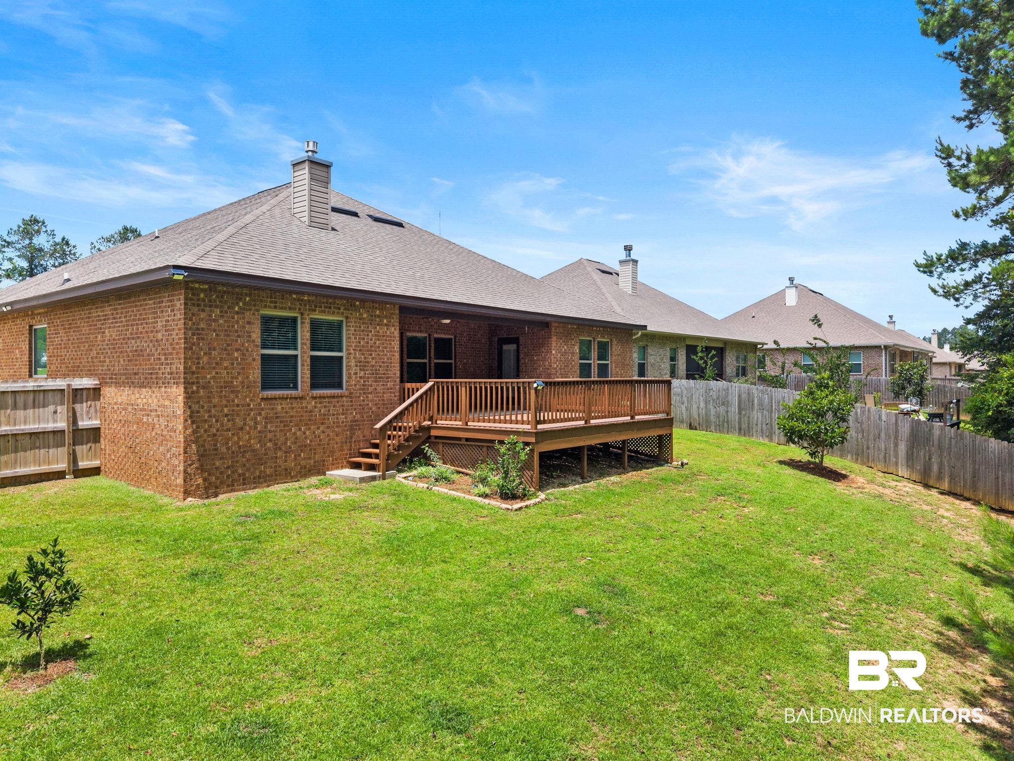 31350 Hoot Owl Road Daphne, AL 36527 - Photo 83 of 94 Expansive backyard featuring a wood-tone deck with railing, a grass lawn, and a privacy fence