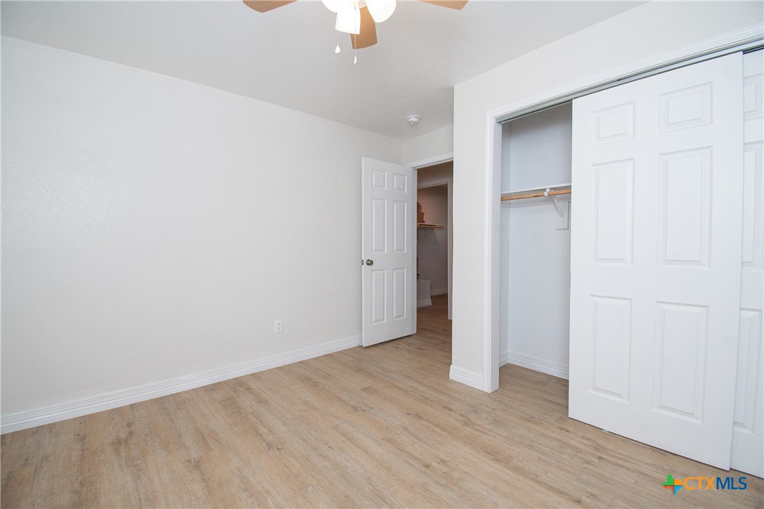 199 Apache Springs Road Briggs, TX 78608 - Photo 11 of 28 an empty room with wooden floor chandelier fan and windows