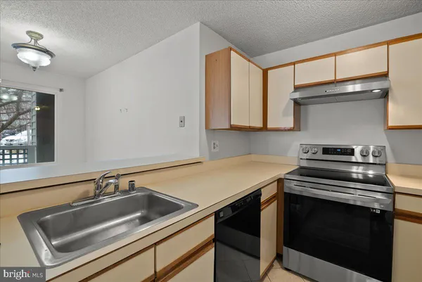 a kitchen that has a sink and a stove with wooden floor