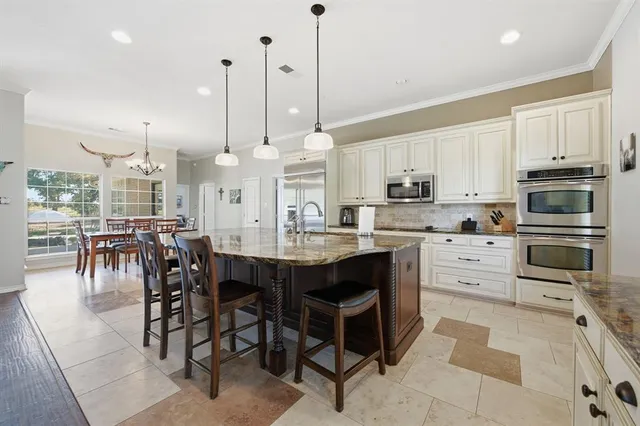 a large kitchen with stainless steel appliances kitchen island granite countertop a stove a sink and a granite counter tops