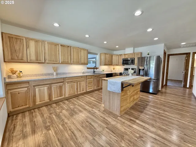 a large kitchen with stainless steel appliances kitchen island granite countertop a stove a sink a refrigerator and blue cabinets