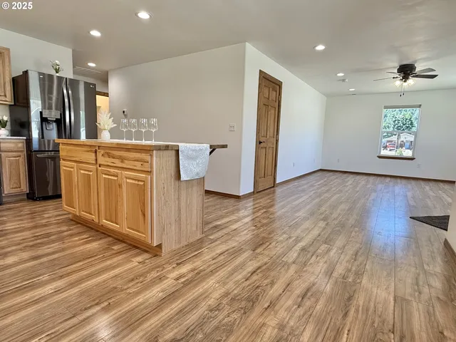 a kitchen with stainless steel appliances granite countertop a stove a sink dishwasher and a refrigerator with wooden floor
